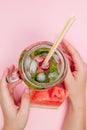 Young woman hands holding freshly squeezed watermelon lemonade of citrus fruits. Female with mason jar full of cold cocktail, mint Royalty Free Stock Photo