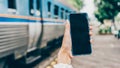 Young woman hands holding mobile at railway station for searching hotel room for booking and payment by internet cashless