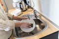 Close up view. Young woman hands with nice manicure washing dishes in the sink in the kitchen using sponge with soap foam Royalty Free Stock Photo