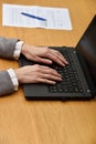 Young woman hands using laptop in a wood table, indoor. Women hands working with laptop, document on the background. Royalty Free Stock Photo