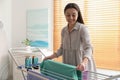 Young woman hanging clean laundry on drying rack at home. Space for text Royalty Free Stock Photo