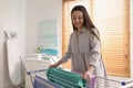 Young woman hanging clean laundry on drying rack at home. Space for text Royalty Free Stock Photo