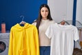 Young woman hanging clothes on racks puffing cheeks with funny face