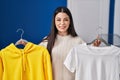 Young woman hanging clothes on racks smiling with a happy and cool smile on face