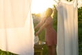 Young woman hanging laundry outdoors. Beautiful girl in red polkadot dress