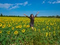 Young woman happily jumping in a field of sunflower