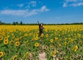 Young woman happily jumping in a field of sunflower