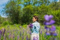 Young woman, happy, standing among the field of violet lupines, smiling, purple flowers. Blue sky on the background. Summer, with Royalty Free Stock Photo