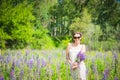 Young woman, happy, standing among the field of violet lupines, smiling, purple flowers. Blue sky on the background. Summer, with Royalty Free Stock Photo