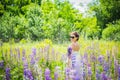 Young woman, happy, standing among the field of violet lupines, smiling, purple flowers. Blue sky on the background. Summer, with Royalty Free Stock Photo