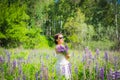 Young woman, happy, standing among the field of violet lupines, smiling, purple flowers. Blue sky on the background. Summer, with Royalty Free Stock Photo