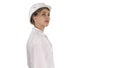 Young woman in hard hat walking and looking around on white background. Royalty Free Stock Photo