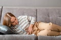 Young woman has abdominal pain lying on couch in working day in office. Acute pain in bloating pms. Teenage girl with pain Royalty Free Stock Photo