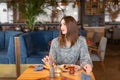 A young woman has Breakfast in a cafe. Oatmeal with salted caramel and prunes, in the original serving. Breakfast