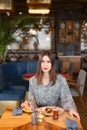 A young woman has Breakfast in a cafe. Oatmeal with salted caramel and prunes, in the original serving. Breakfast