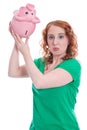 Young woman has money problems - isolated on green with piggy ba