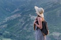 Young woman in hat and with backpack on background nature. Harmony and peace concept