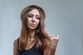 Young woman in hat and black shirt is proudly posing isolated on gray background in a studio close up Royalty Free Stock Photo