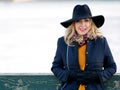 Young woman in hat and coat walking. Portrait of the blonde on the street, smiling and fun