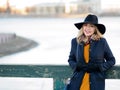 Young woman in hat and coat walking. Portrait of the blonde on the street, smiling and fun