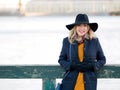 Young woman in hat and coat walking. Portrait of the blonde on the street, smiling and fun