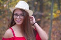 Young woman hat glasses autumn red dress orange forest portrait