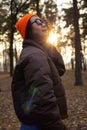 Young woman in hat and jacket walking in the forest at sunset.