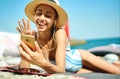 Young woman in hat laughting and talking on video call on smartphone, chatting with friends at beach during summer Royalty Free Stock Photo