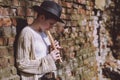 Young woman in a hat playing the flute in the street. Hipster girl outdoors Royalty Free Stock Photo