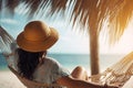 Young woman in hat relaxing in hammock on the beach. Vacation concept, rear view of a woman relaxing and enjoying the sun on