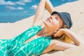 Young woman in hat relaxing on the sand beach. Fashion model woman posing on the sand dunes. Blue summer sky as Royalty Free Stock Photo