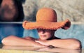Young woman in hat resting by the side of pool