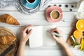 Young woman have a breakfast with fresh croissants, coffee and fruits and her hands drawing or writing with ink pen Royalty Free Stock Photo