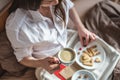 Young woman have a romantic Breakfast in morning bed. Coffee and word love from cookies. Surprise on Valentine`s day Royalty Free Stock Photo