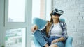 Young woman have VR experience using virtual reality headset sitting in chair on balcony Royalty Free Stock Photo
