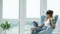 Young woman have VR experience using virtual reality headset sitting in chair on balcony Royalty Free Stock Photo