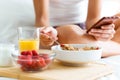 Young woman having breakfast and texting with her smartphone in the bedroom. Royalty Free Stock Photo