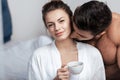 Young woman having coffee with boyfriend in bed Royalty Free Stock Photo