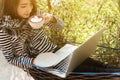 Young woman having coffee in hammock while use laptop, freelance