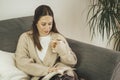 Young woman having a cup of coffee while reading a book on the sofa at home Royalty Free Stock Photo