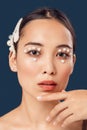 Freestyle. Young woman eyes decorated with perls standing isolated on dark blue posing sensual close-up