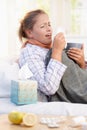 Young woman having flu laying in bed sneezing Royalty Free Stock Photo