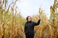 Young woman having fun on pumpkin fair at autumn. Person walking among the dried corn stalks in a corn maze Royalty Free Stock Photo