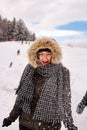 Young woman having fun in the snow smiling as snow is thrown towards her; recreational active winter concept