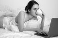 Young woman having good time in bed on the living room with coffee and laptop. Royalty Free Stock Photo