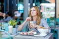 Young woman having healthy breakfast in outdoor cafe Royalty Free Stock Photo