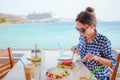 Young woman having lunch with delicious fresh greek salad, frappe and brusketa served for lunch at outdoor restaurant Royalty Free Stock Photo