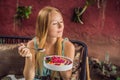 Young woman having a mediterranean breakfast seated at her sofa and eats Healthy tropical breakfast, smoothie bowl with Royalty Free Stock Photo