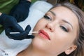 Young woman having permanent makeup on her lips at the beautician salon Royalty Free Stock Photo