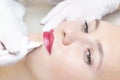 Young woman having permanent makeup on her lips at the beauticians salon. Permanent Makeup Tattoo. Royalty Free Stock Photo
